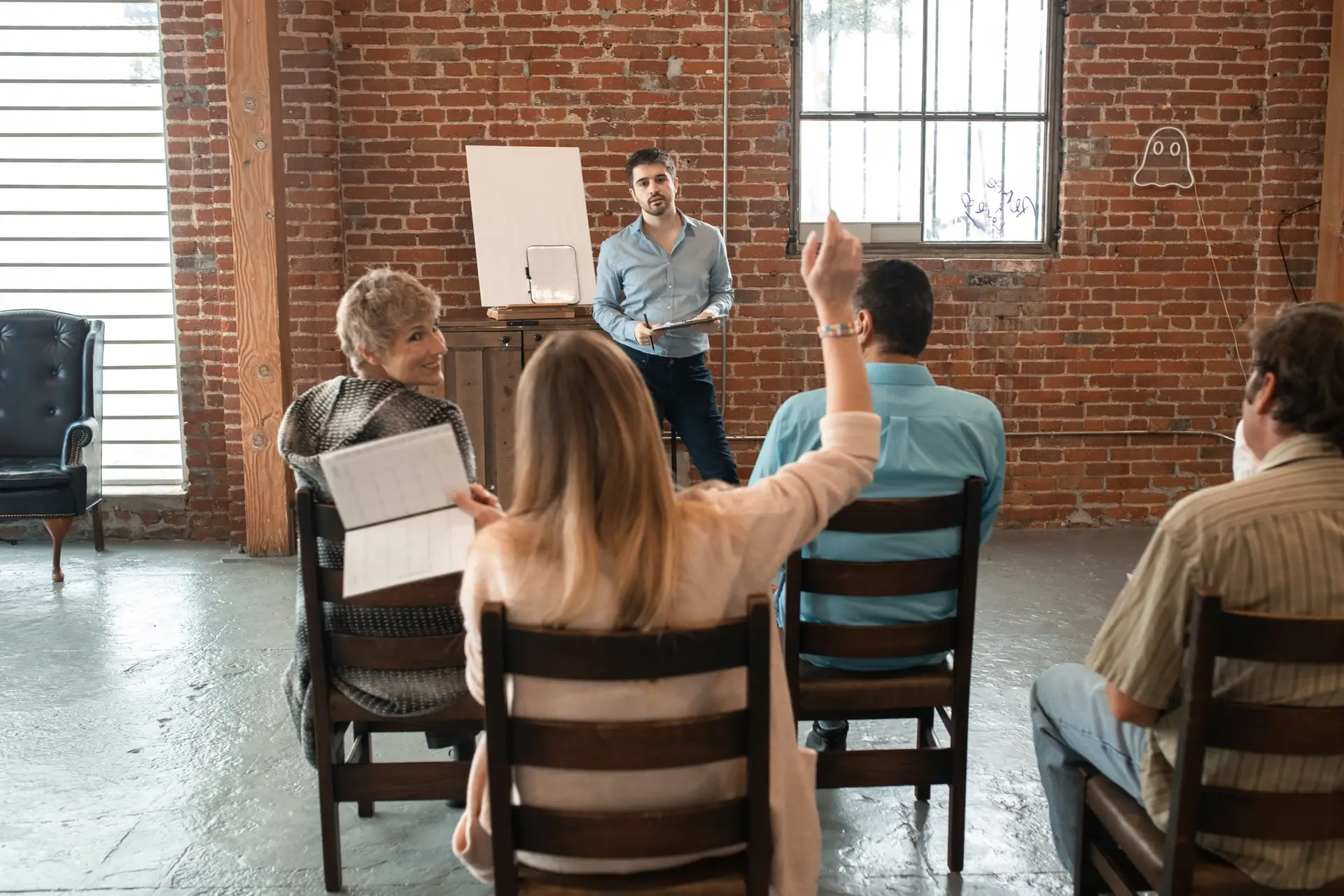 Un facilitador conversa con un grupo de adultos sentados, durante un taller.